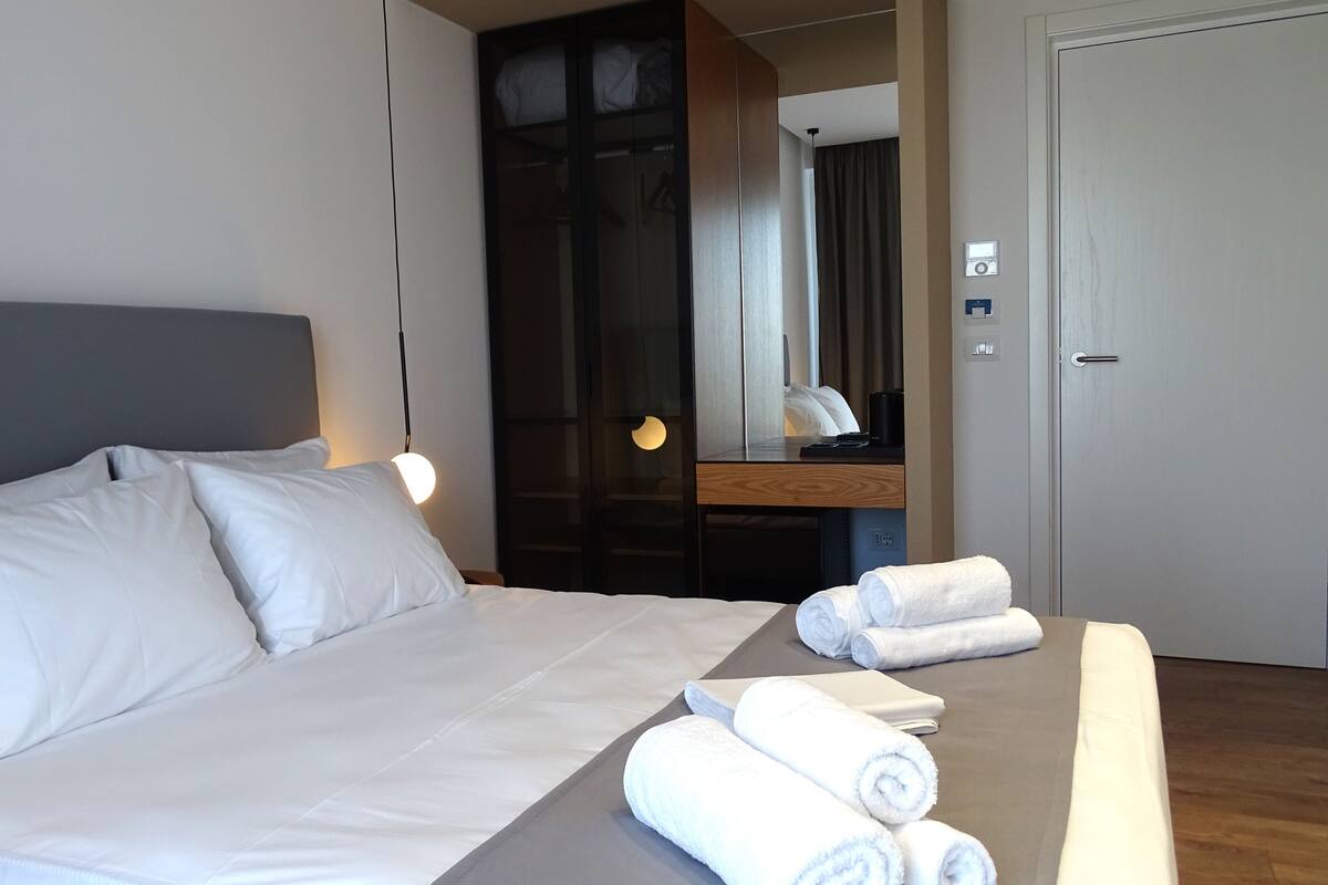 A hotel room with a large bed, a desk, and a mirror.