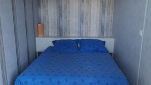 A bedroom with a bed, a nightstand, and a wooden wall panel.