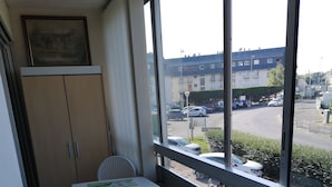 A small kitchenette with a table and chairs, a coffee maker, and a toaster. A window offers a view of a parking lot and buildings outside.