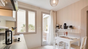 Une cuisine compacte avec un coin repas, une machine à café et une vue sur le balcon extérieur.