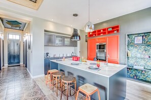 Une cuisine moderne dotée d’un îlot central, de tabourets de bar et d’un mur d’accent rouge.