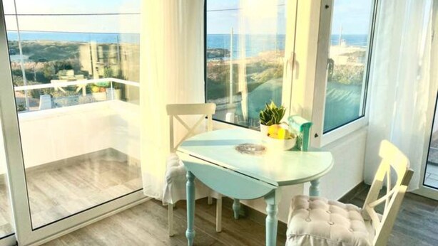 Ein Balkon mit Glastür, einem kleinen Tisch und zwei Stühlen.