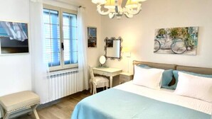 Ein Schlafzimmer mit Bett, Schreibtisch, Stuhl, Heizkörper und einem Fenster mit Vorhängen.