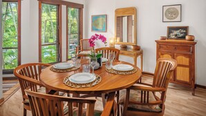 A dining area with a round wooden table set for four, surrounded by wooden chairs.