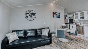Un salon moderne avec un canapé en cuir noir, une table basse ronde et un coin repas comprenant une petite table et des chaises.