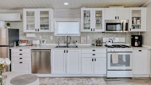 Une cuisine moderne avec des meubles blancs, des appareils en acier inoxydable et un îlot central.