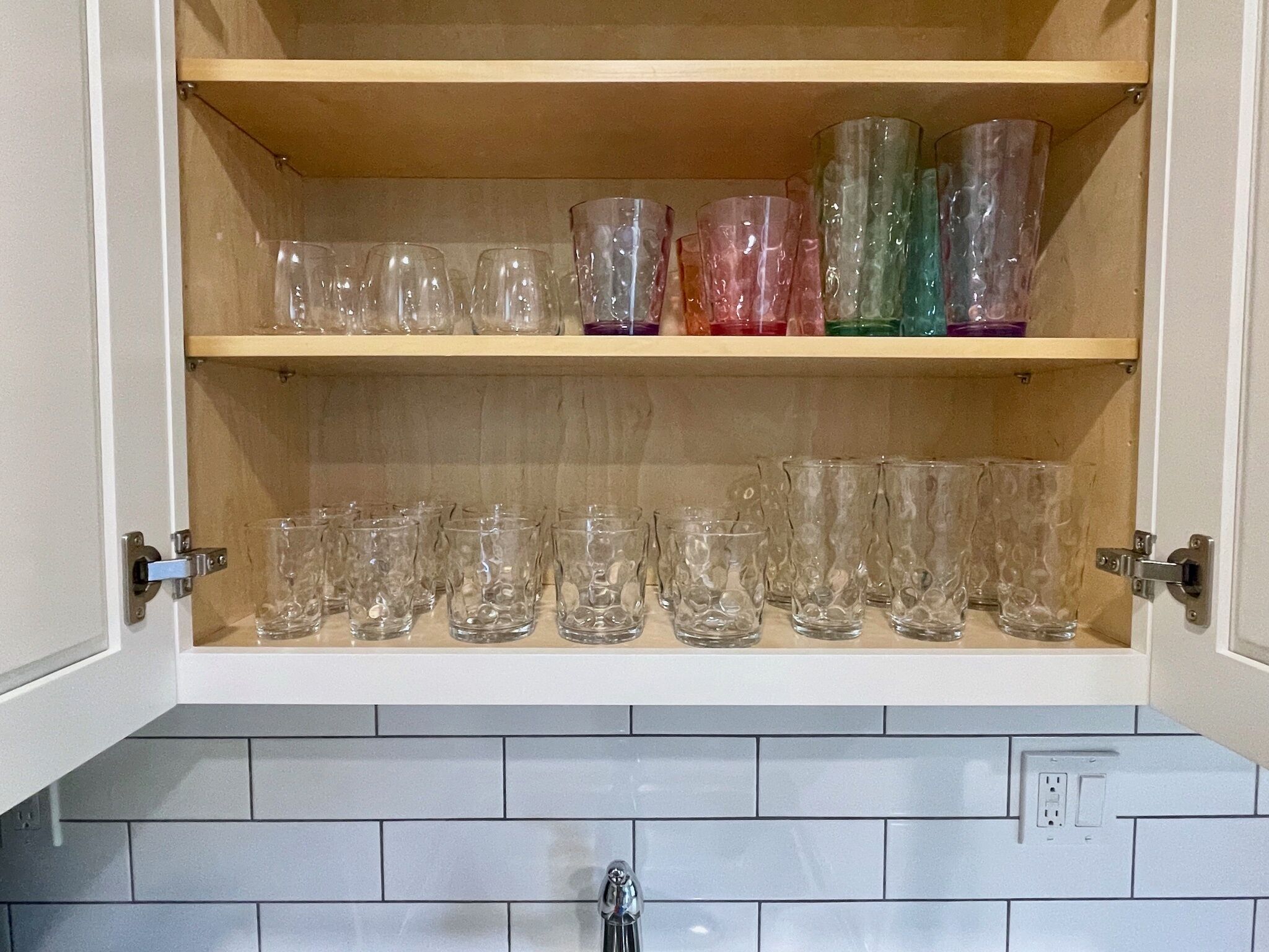 Un meuble de cuisine doté de deux étagères où sont rangés différents objets en verre.
