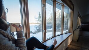A person sitting by a large window with a view of a snowy landscape.