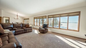 A spacious living room with a large sectional sofa, a single armchair, and a dining table.