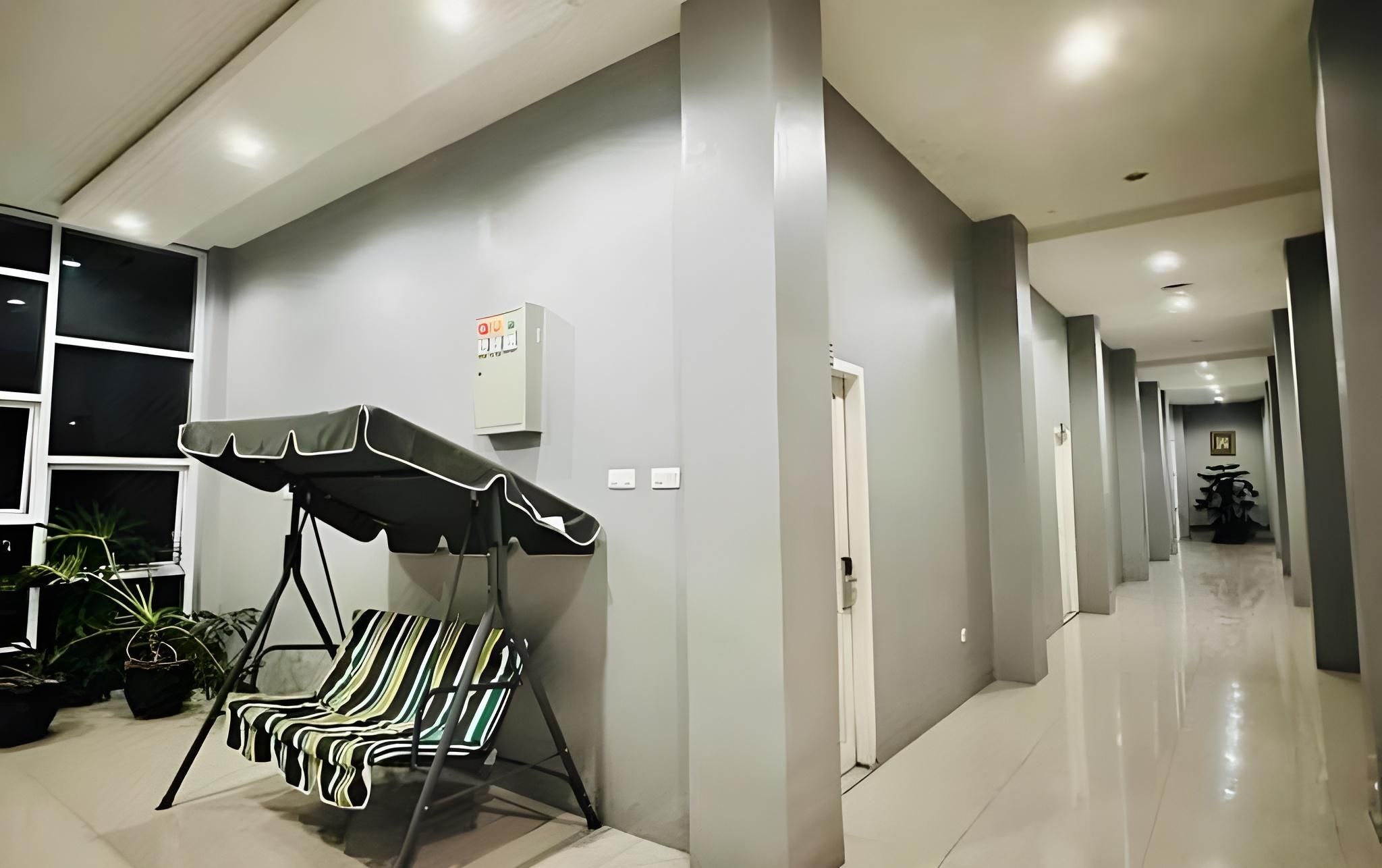 A corridor with a massage chair, potted plants, and a wall-mounted electrical box.