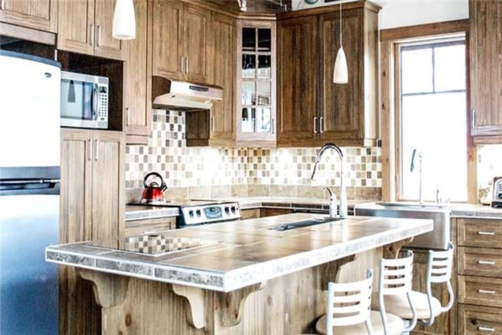 A kitchen with wooden cabinets, a microwave, a stove, and a large island with chairs.