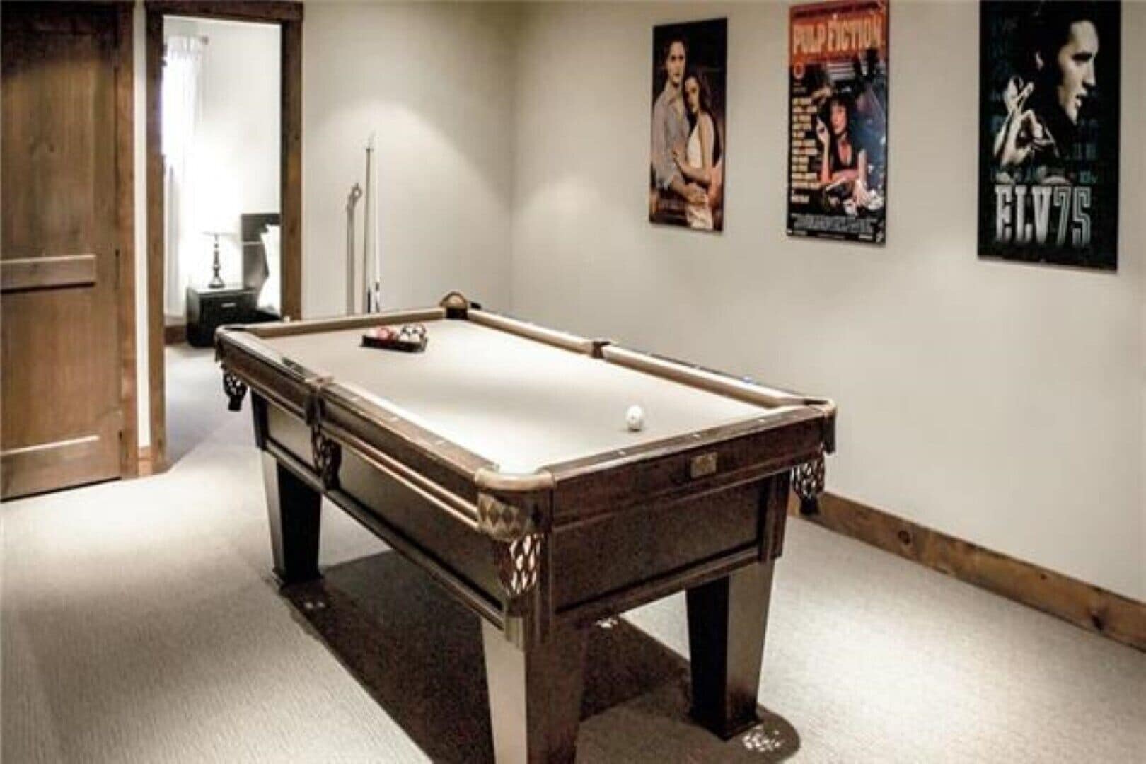 A pool table in a room with a wooden door and a poster on the wall.