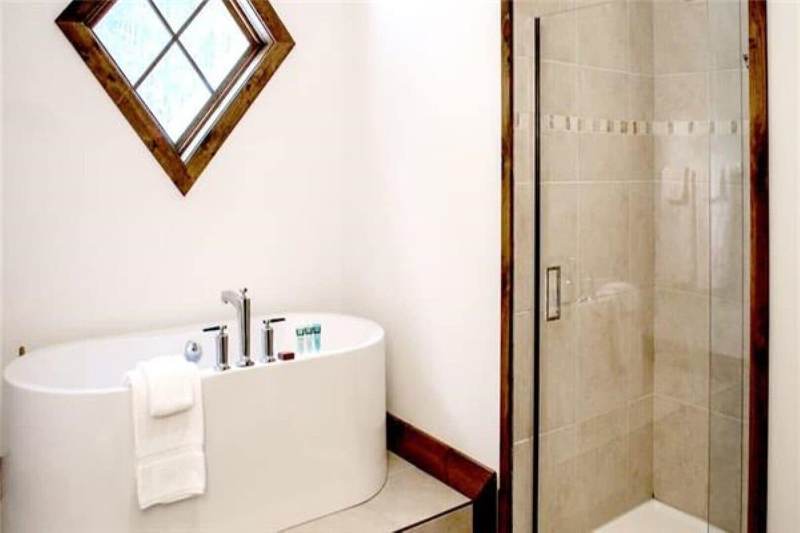 A bathroom with a freestanding bathtub, a glass shower enclosure, and a small window above the tub.