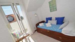 Ein Schlafzimmer mit einem Bett, einem Stuhl, einer Lampe und einem Fenster.