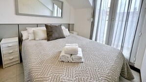 A bedroom with a large bed, a nightstand, a mirror, and a window with curtains. - Apartamento con piscina junto a la playa - La Aren (Arnuero)