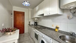 A compact kitchen with a washing machine, a sink, and a microwave.