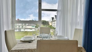 A dining table set for two with a view of buildings and greenery outside.