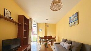 Una sala de estar con televisor, sofá, mesa de centro y comedor.