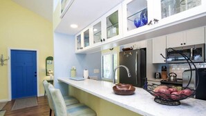 A modern kitchen with white cabinets, a black refrigerator, and a stainless steel sink. - A Peace of Heaven (Sanibel)