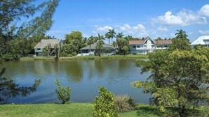 A residential area with houses near a calm lake, surrounded by greenery and palm trees. - A Peace of Heaven (Sanibel)