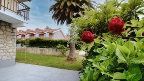 A residential area with a stone wall, a concrete patio, and a row of houses in the background.
