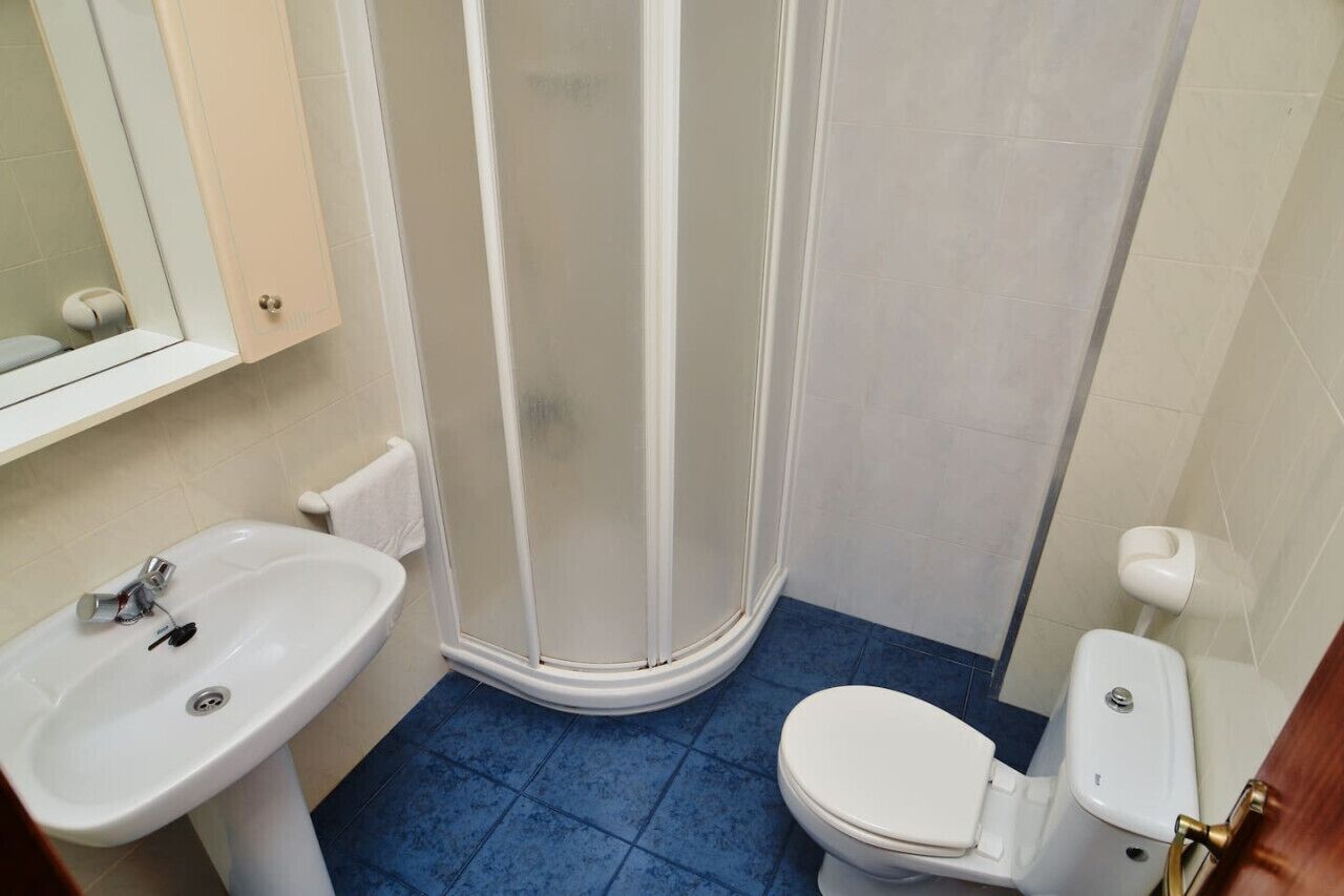 Een badkamer met een wit wastafelmeubel, toilet en douchecabine.