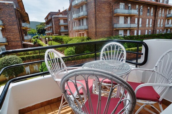 Relax on the balcony with a seating area featuring wicker chairs and a view of the surrounding neighborhood.