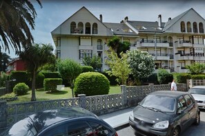 Stunning multi-story building with a central entrance and two wings, surrounded by lush greenery and manicured bushes.