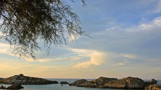 A beach with rocky formations and calm water.