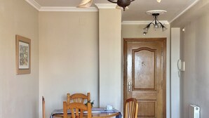 A dining area with a wooden table and chairs, a framed picture on the wall, and a wooden door in the background. - Apartamento con vistas al mar - Pineda 6404 (Noja)