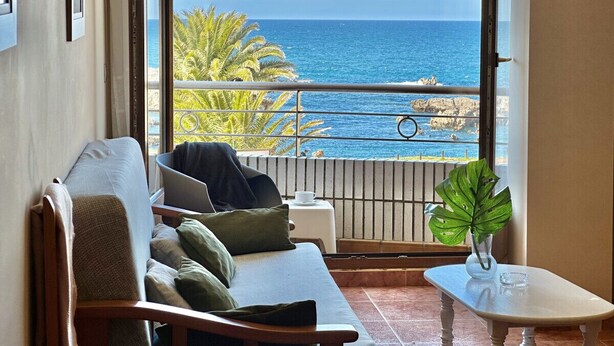 A balcony with a view of the ocean, a sofa, a table, and a potted plant. - Apartamento con vistas al mar - Pineda 6404 (Noja)