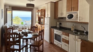 A kitchen with wooden cabinets, a microwave, and a dining area with a table and chairs.