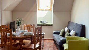 Un coin repas avec une table dressée pour quatre personnes, un canapé et une fenêtre donnant sur un beau paysage.