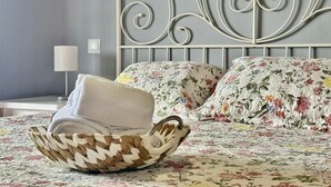 Ein ordentlich bezogenes Bett mit Blumenmuster, einem Metall-Kopfstück und einem gewebten Korb mit Handtuch.