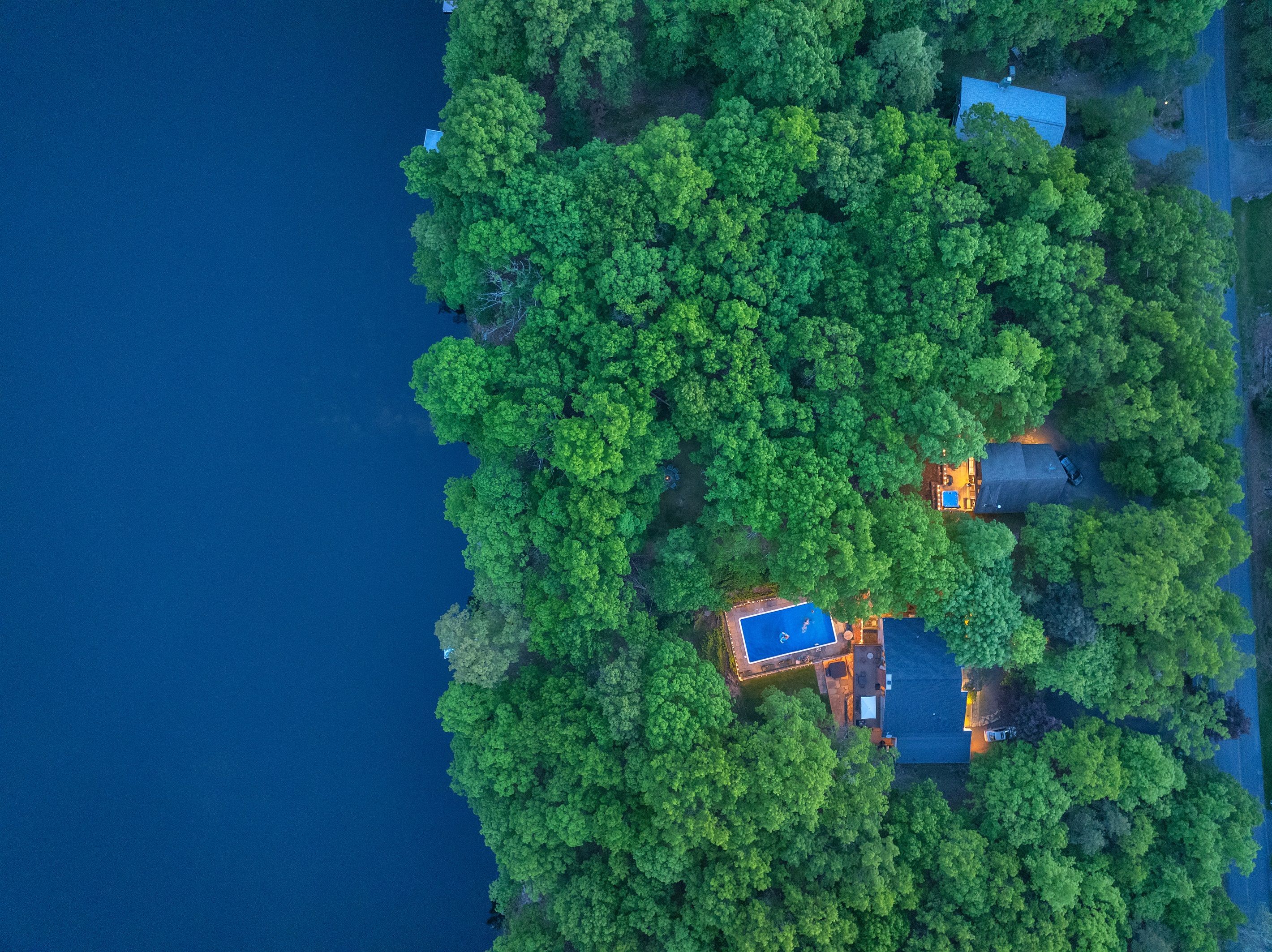 Eine Vogelperspektive einer abgelegenen Insel mit üppiger Vegetation, einem Swimmingpool und zwei Gebäuden.