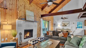 Un salon chaleureux avec une cheminée, des murs en bois et un ventilateur de plafond.