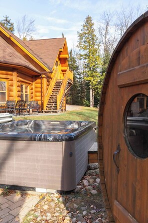 Eine Holzhütte mit Whirlpool und Sitzbereich im Freien.
