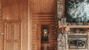 A wooden hallway with a stone fireplace and a painting on the wall.