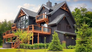 A large, dark wooden house with multiple balconies and a well-maintained garden. - Laurentian Chalet: 4K Cinema, Sauna & Hot Tub (Morin-Heights)