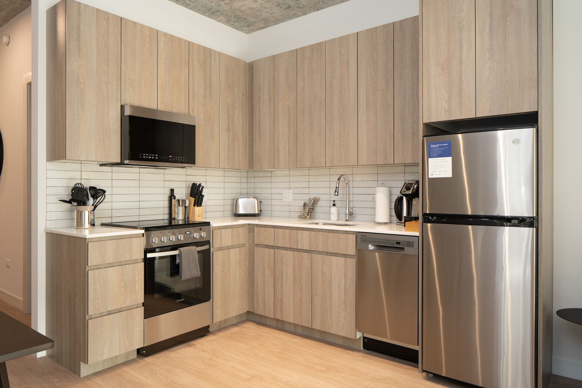 A modern kitchen with wooden cabinets, stainless steel appliances, and a tiled backsplash.