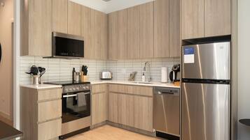 Une cuisine moderne avec des meubles en bois, des appareils électroménagers en acier inoxydable et un revêtement mural en carreaux.