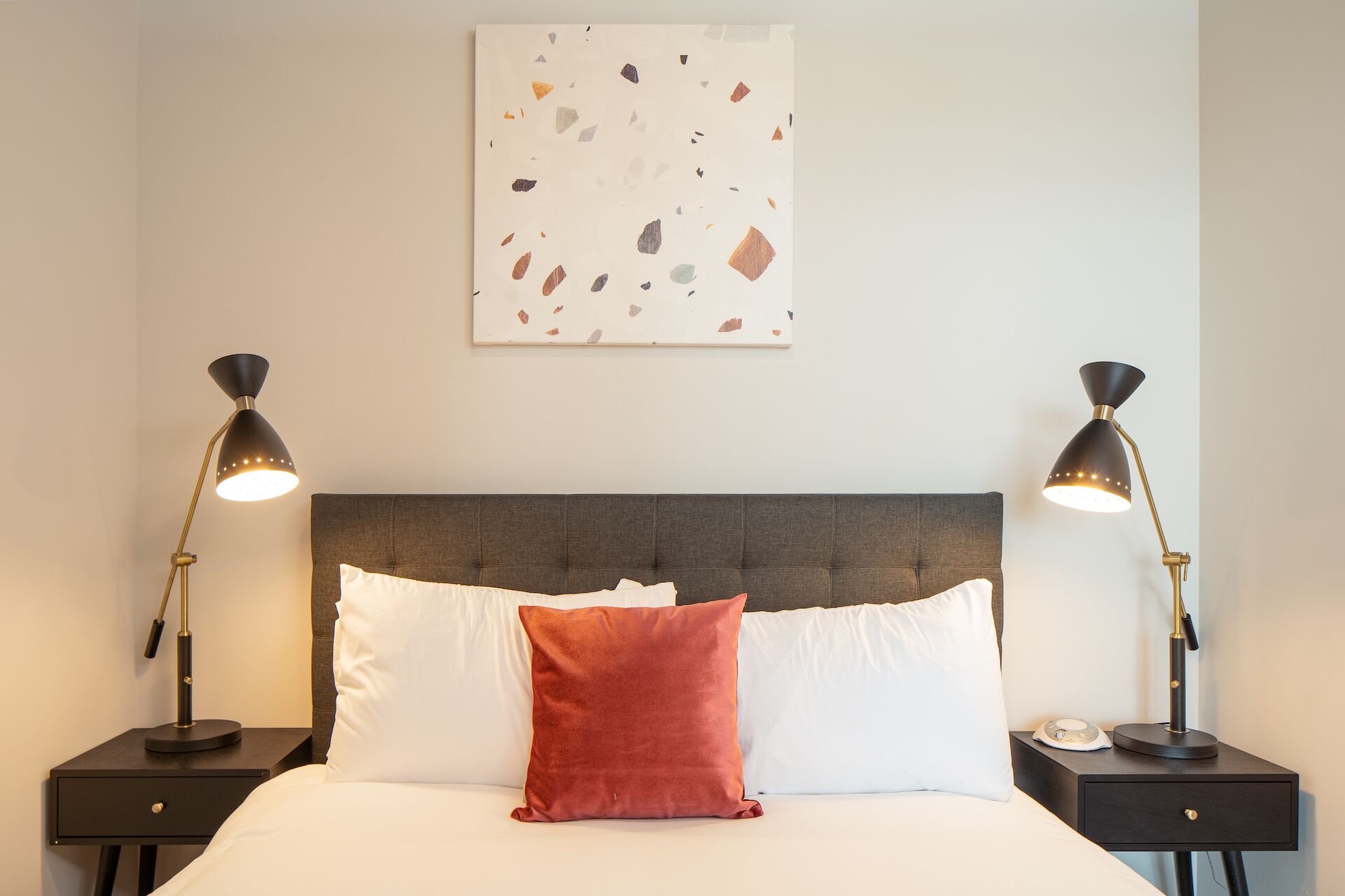 Una habitación de hotel con una cama grande, dos mesitas de noche y dos lámparas.