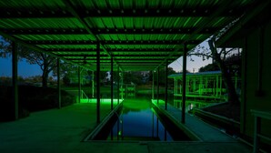A covered outdoor area with a pool, metal structures, and trees. - Hidden Harbor-Lakefront on Secluded Cove w/Dog Run (Kingsland)