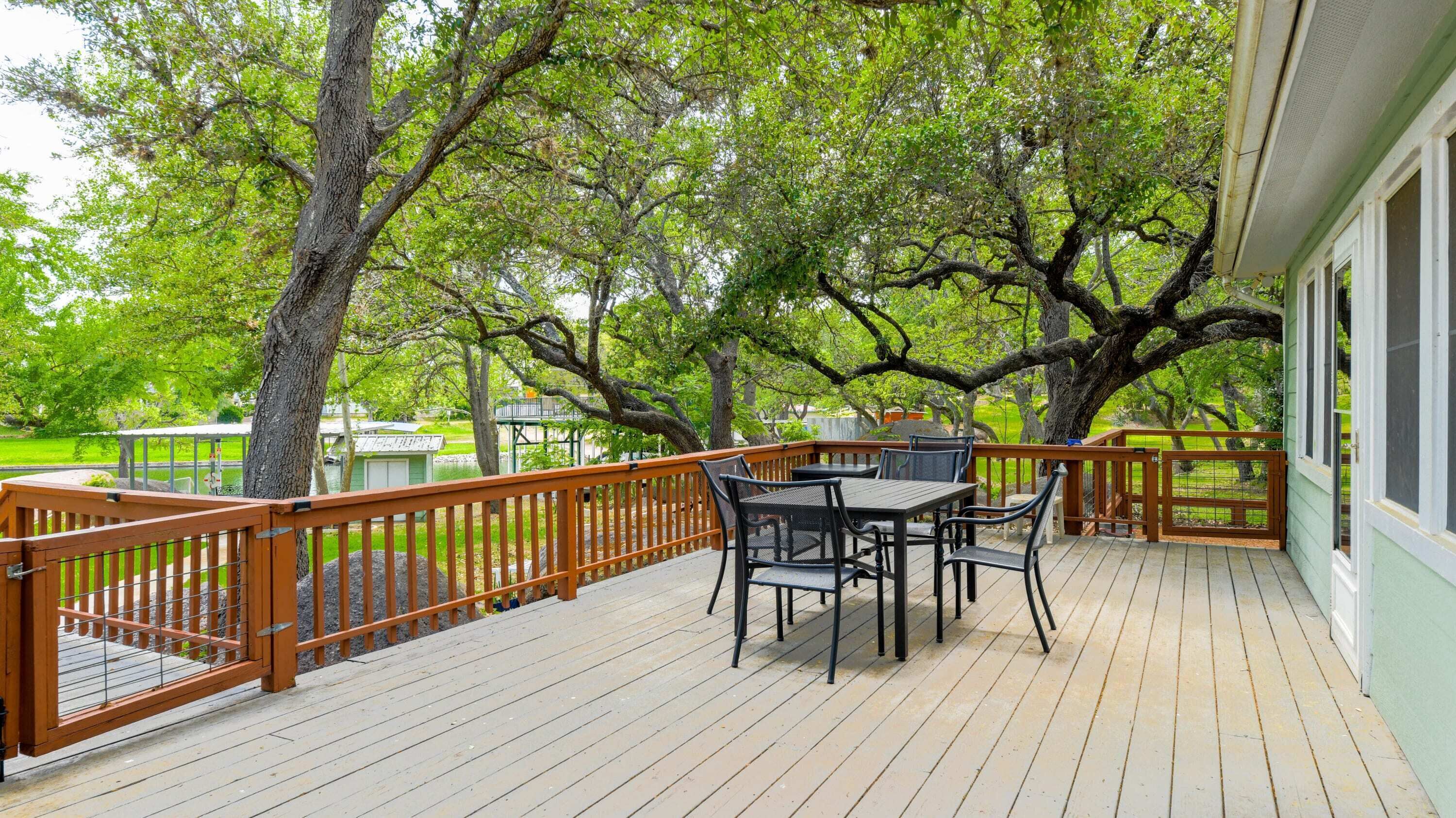 A wooden deck with a table and chairs, surrounded by trees.