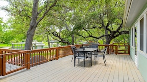 Een houten terras met een tafel en stoelen, omringd door bomen.