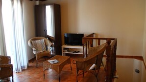 A living room with wicker furniture, a television, and a staircase. - Cozy House (Lagos)