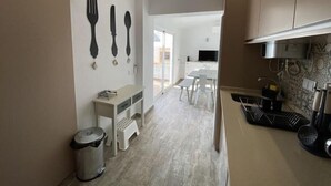 A modern kitchen with white cabinets, a countertop with a kettle, and a trash bin. - Friendly House (Lagos)