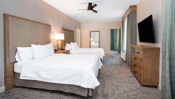 A hotel room with two beds, a ceiling fan, a TV, and a wooden dresser.