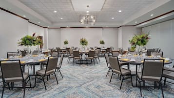 A conference room with multiple round tables, each set with chairs, glasses, and cutlery.