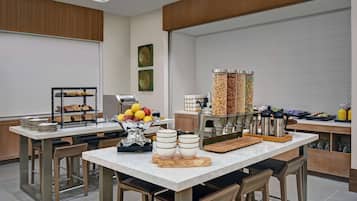 A modern dining area with a marble table, multiple seating options, and a variety of food and beverage dispensers.